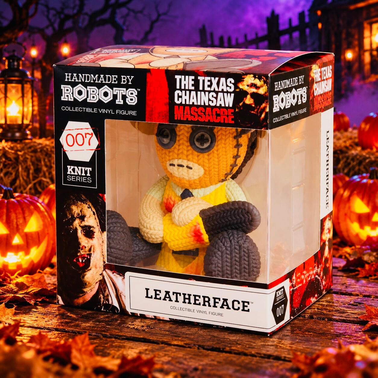 Boxed Leatherface figure holding a chainsaw, displayed on a wooden platform with glowing pumpkins and purple mist.