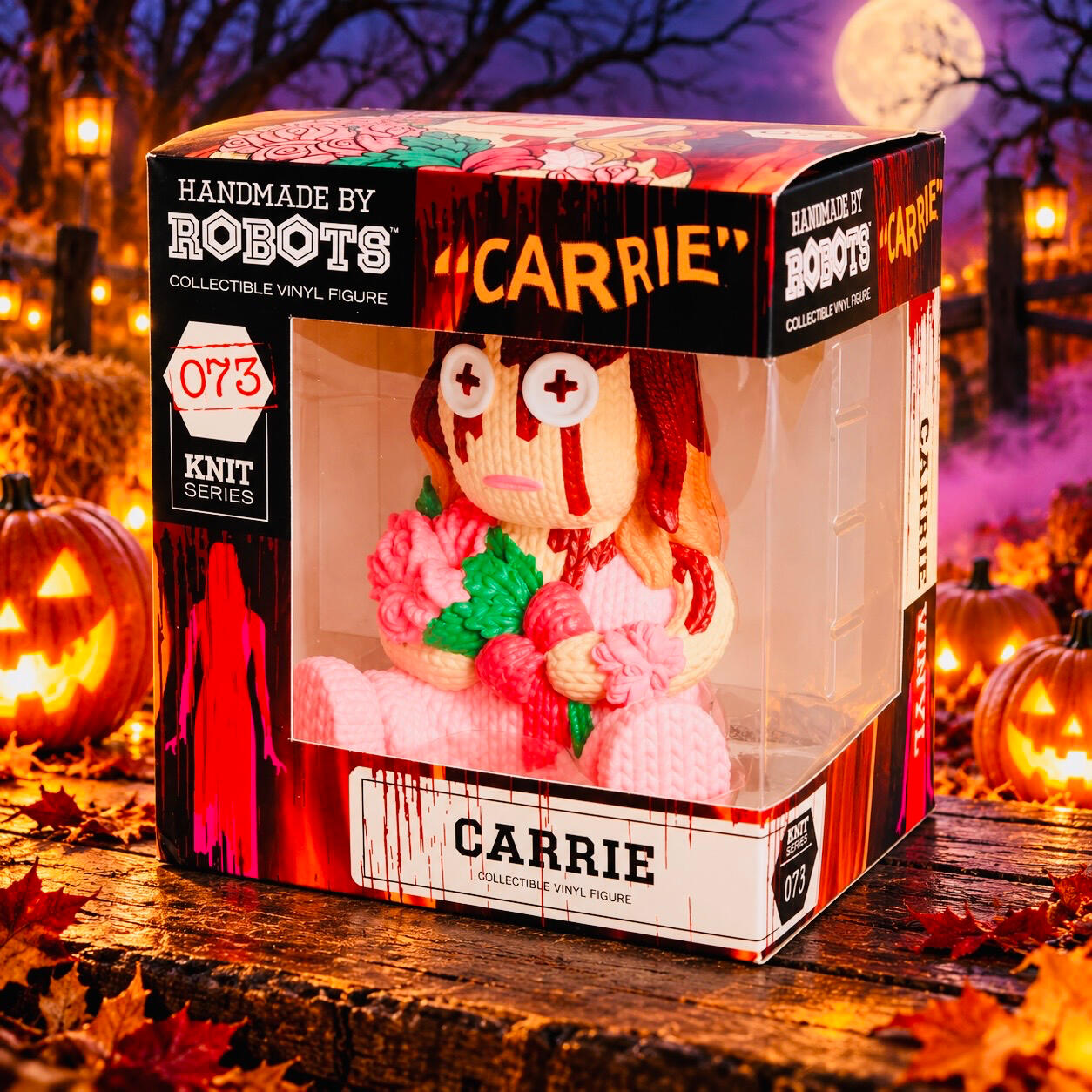 Boxed Carrie figure in a pink dress holding flowers, surrounded by glowing pumpkins and purple Halloween mist.
